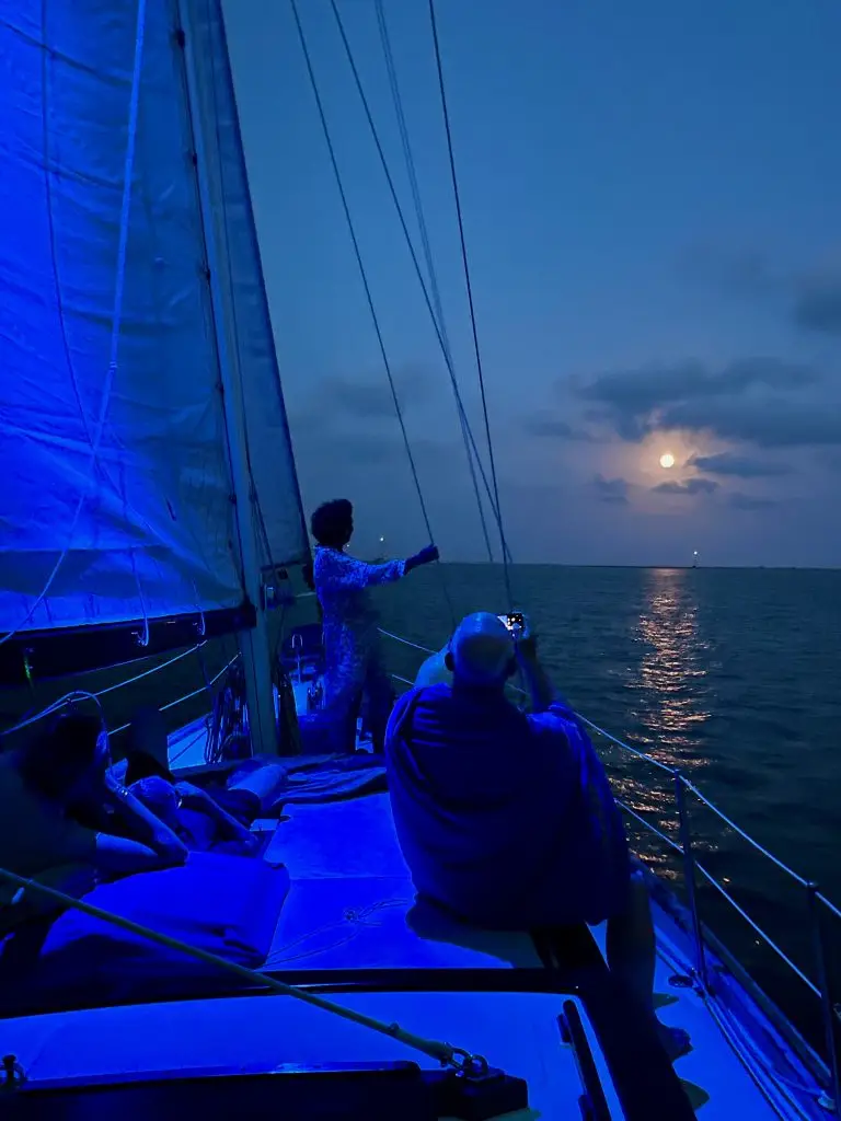 velero Butterfly navegando de noche con luna llena en la Bahía de los Alfacs, Delta del Ebro