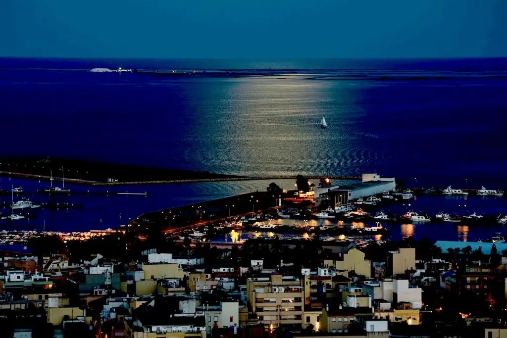 velero Butterfly navegando de noche con luna llena en la Bahía de los Alfacs, Delta del Ebro